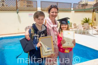 Uma mãe com seus 2 filhos que completaram um curso de línguas