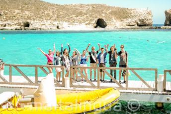 Um grupo de alunos acenando perto do barco em Blue Lagoon, Comino