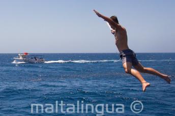 Um estudante que faz um salto do barco