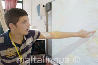 Estudante apontando para um mapa na sala de aula