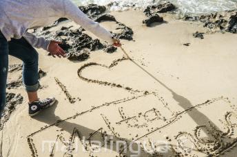 Um aluno fazendo um coração na areia Maltalingua
