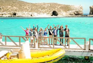 Um grupo de alunos acenando perto do barco em Blue Lagoon, Comino