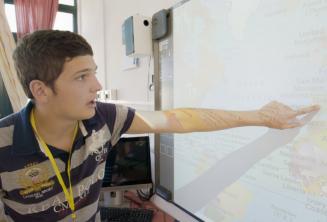 Estudante apontando para um mapa na sala de aula
